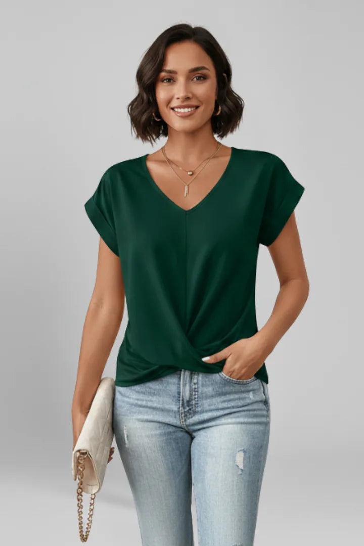 Model wearing a deep green V-neck top with rolled sleeves and twist-front hem styled with denim jeans