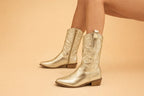 Close-up side profile of metallic gold cowboy boots showing pointed toe and stitched shaft detail