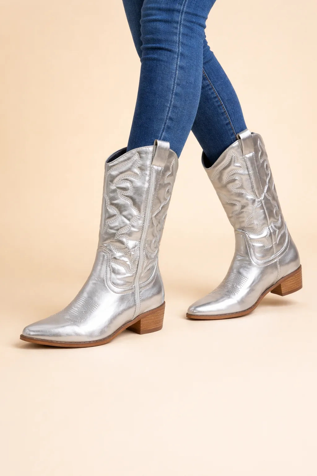 Silver metallic cowboy boots worn with skinny jeans, showing pull tab and embroidered shaft from the side