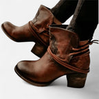 Pair of brown leather western ankle boots with wrap-around lacing and stacked block heel, worn on model