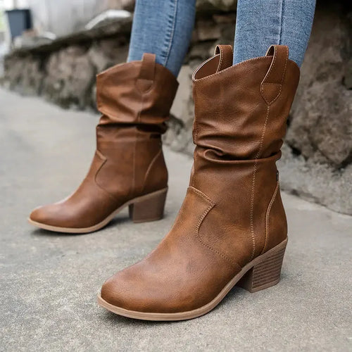 Side view of camel brown slouch-style western boots with stacked block heel, worn with skinny jeans tucked in
