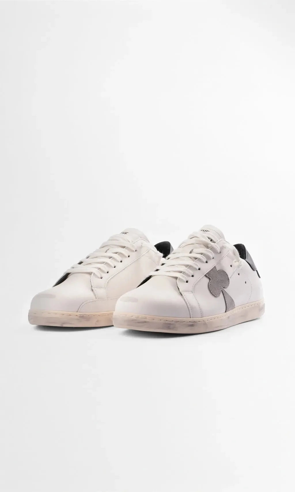 Front three-quarter view of two white leather sneakers highlighting the chunky cream sole and black heel accent.