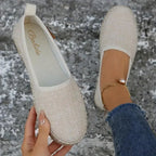 Inside view of a beige espadrille flat held in hand, revealing soft textile lining and brand label