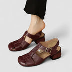 Side view of burgundy leather fisherman-style sandal with woven straps, buckle closure and block heel, worn on foot
