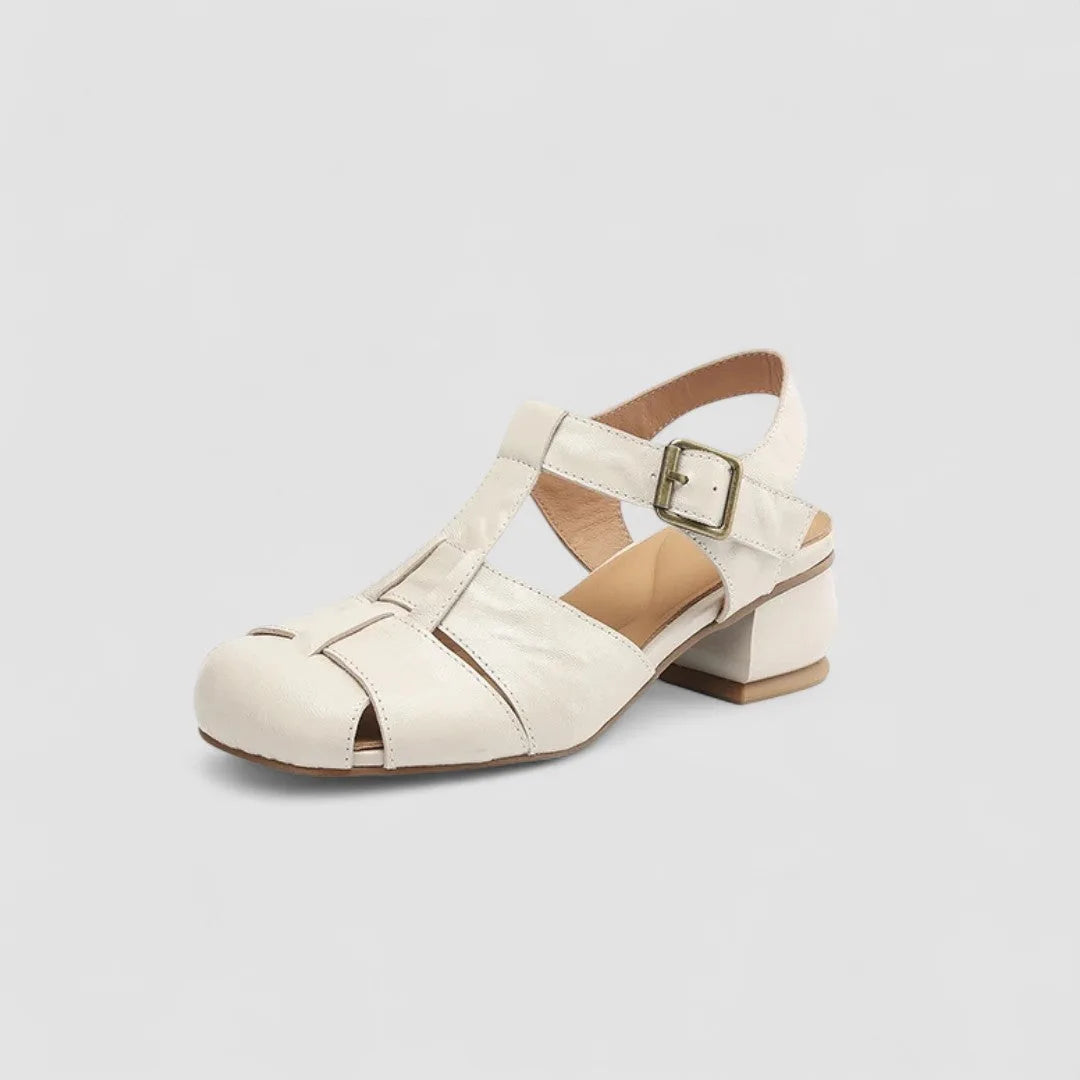 Angled studio shot of beige leather fisherman sandal with brass buckle, cushioned footbed and block heel