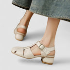 Close-up angled view of black leather sandal highlighting woven straps and bronze buckle detail