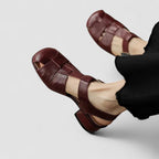 Back view of beige leather sandals on feet showing slingback strap and block heel with denim hem