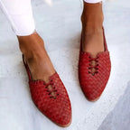 Red woven leather flats with pointed toe and lace-up front, worn with white ankle-length jeans