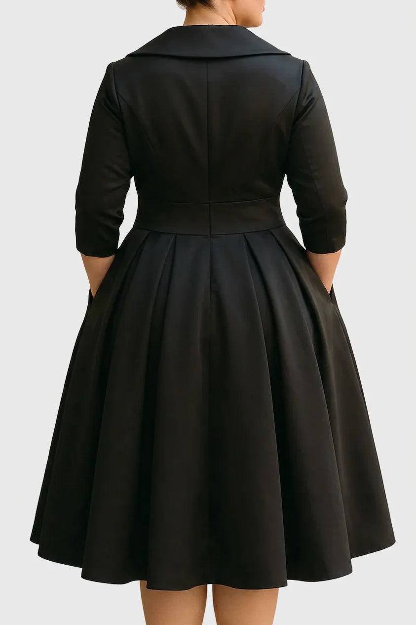Back view of the midi dress in black satin, showing the fitted bodice seaming, waistband and the deep box-pleated skirt.