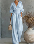 Woman adjusting her hair while wearing the white wrap jumpsuit on a sunny beach
