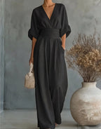 Detail shot of the ruched waist tie on the cream wrap jumpsuit against a neutral wall