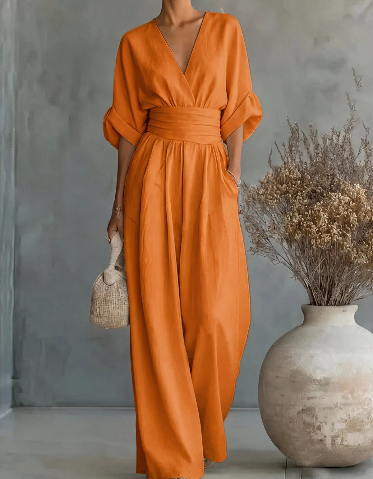 Woman reaching down to arrange a picnic blanket while wearing the cream wrap jumpsuit