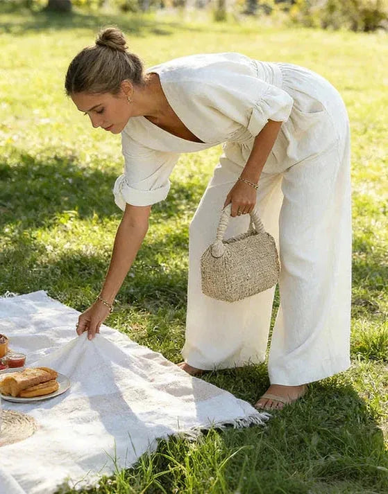 Close view of the cream jumpsuit's gathered waist and puff sleeves while styling a picnic setup outdoors