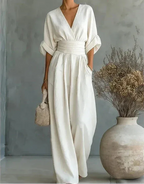 Front view of a woman in a white wrap jumpsuit with deep V neckline and flowing wide-leg trousers