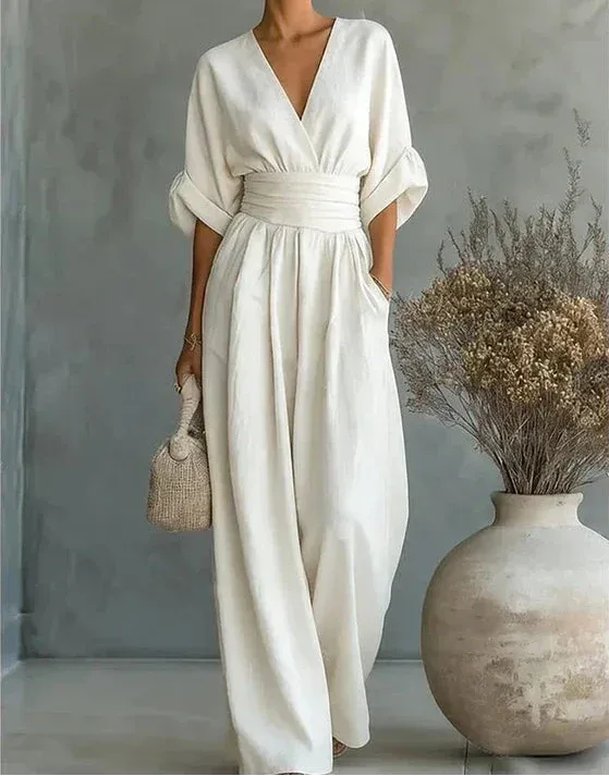 Front view of a woman in a white wrap jumpsuit with deep V neckline and flowing wide-leg trousers